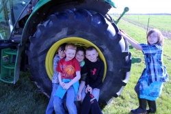 School children pose inside tractor wheel