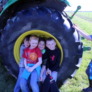 School children pose inside tractor wheel